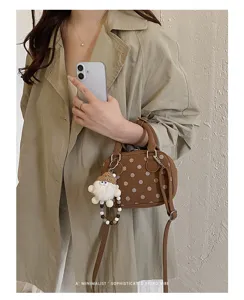 Close-up detail of retro polka dot faux suede bowling bag with cute doll keychain charm
