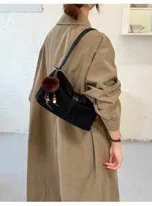 Dettaglio della borsa a spalla in camoscio nero con elegante fiocco e grazioso ciondolo pon-pon soffice.