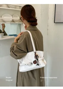 Vue détaillée d'un sac porté épaule chic en cuir blanc avec sangle rétro et pendentif.