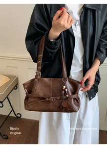 Gros plan d'un sac marron en cuir souple avec une boucle de ceinture et de jolis pendentifs.