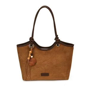 Brown vintage suede tote bag detail featuring wooden bead tassel charm and leather straps.