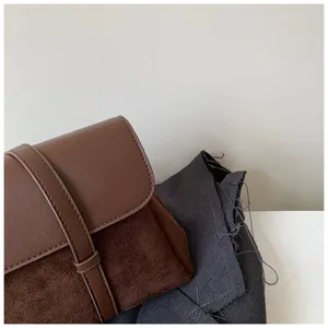 Close-up of brown leather and suede retro shoulder bag detail showing texture and fine strap.