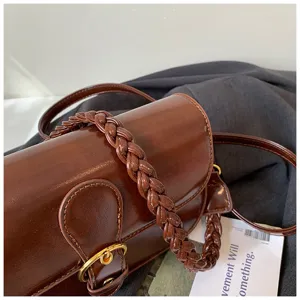 Detailansicht der braunen Leder-Umhängetasche mit geflochtenem Griff und Metallschnalle.