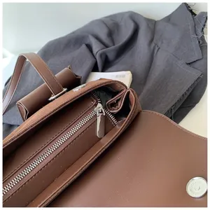 Close-up detail of a brown retro suede shoulder bag showing metal zipper and leather texture.