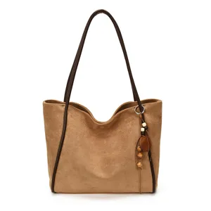 Vintage suede shoulder bag detail, brown tote with leather handles and wooden bead charm.