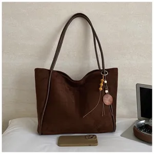 Detailed view of dark brown suede tote bag featuring wooden bead tassel charm and handles.