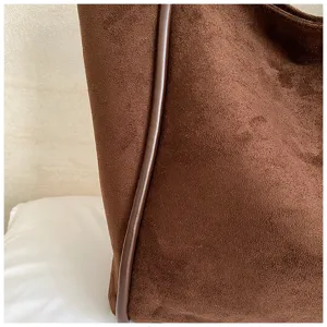 Brown suede tote bag detail, featuring soft fabric texture and elegant dark leather piping.