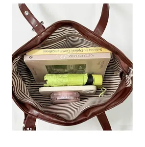 Detail shot showcasing the large capacity interior of the brown leather tote bag with striped lining.