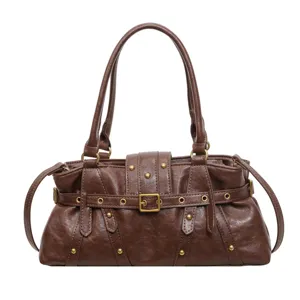Bolso de hombro retro marrón de cuero sintético con hebillas metálicas y remaches detallados.