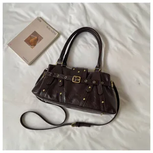 Bolso de hombro de cuero vintage marrón oscuro con tachuelas metálicas y hebillas.