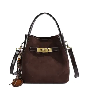 Brown suede bucket bag detail showcasing luxury turn-lock clasp closure, top handle, and tassel.