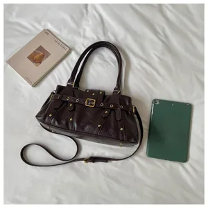Vista detallada del bolso de hombro vintage marrón oscuro con tachuelas, estilo punk.