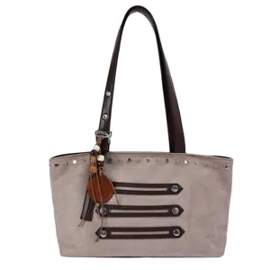 Detailed view of the gray suede shoulder bag with brown leather handles, studs and wooden charm.