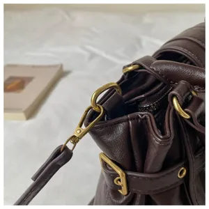 Detalle en primer plano del bolso de mano vintage marrón con herrajes metálicos y hebillas.