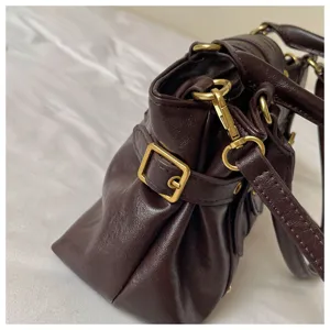 Vista detallada del bolso de hombro estilo moto retro marrón oscuro con herrajes metálicos.