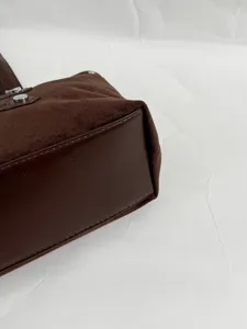 Brown suede leather handbag detail, vintage rivet tote bag side view, premium quality.