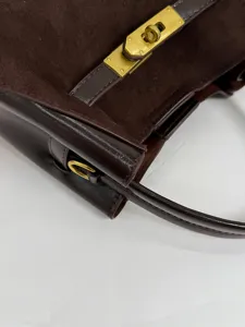 Elegante donkerbruine suède schoudertas met gouden metalen hardware details.