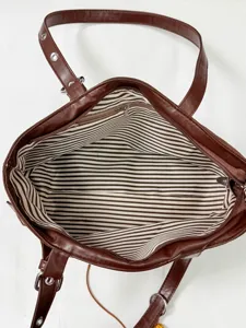 Detailed view of the brown leather tote bag interior, showing striped lining and metal zipper.