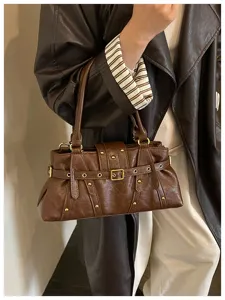 Primer plano del bolso de hombro marrón estilo moto retro con tachuelas elegantes.