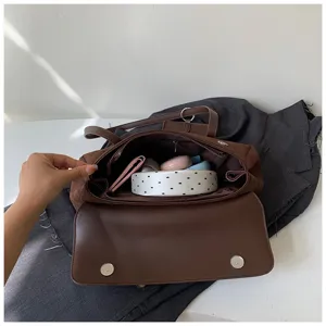Retro brown suede shoulder bag detail view showing interior capacity and chic design.