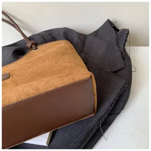 Brown suede shoulder bag detail, stylish contrast leather bottom and delicate knot handle.