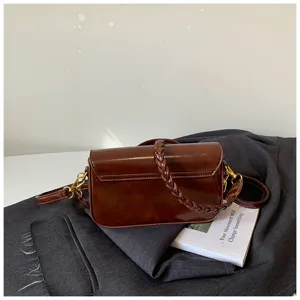 Braune glänzende Ledertasche Detail, elegante geflochtene Griff und schöne Metallbeschläge.