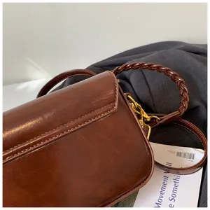 Detailansicht der braunen Leder Achseltasche mit geflochtenem Griff und Goldbeschlag.