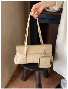 Detailed shot of the chic beige shoulder bag with a small coin purse pendant in use.