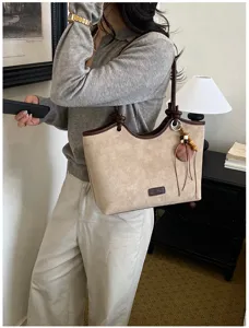 Retro suede tote bag for women, chic shoulder handbag with contrast brown trim and charm.