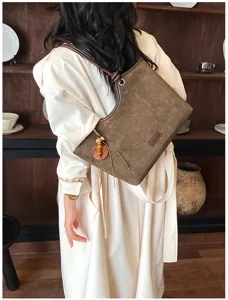 Retro brown suede shoulder bag detail, stylish women's crossbody tote with beaded charm.