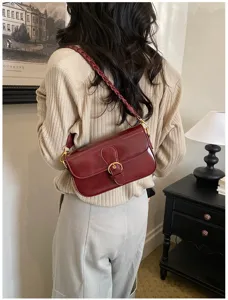Ansicht der schicken burgunderroten Schultertasche mit geflochtenem Riemen und Metallschließe.