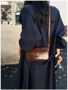 Nahaufnahme einer braunen Vintage Leder Umhängetasche mit Retrometallschnalle im Freien.
