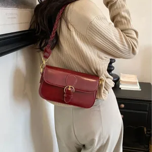 Weinrote Leder-Umhängetasche für Damen, stilvolle Baguette-Tasche am Model getragen.