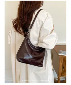 Detail view of dark brown soft leather shoulder bag with chic dumpling shape and metal hardware.