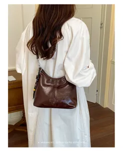 Brown patent leather shoulder bag for women, stylish hobo dumpling purse with beaded strap.