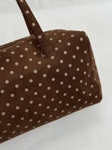 Gros plan détaillé sur le sac Boston marron avec un joli motif à pois blancs et une poignée.