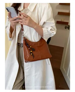 Detailed view of the brown leather shoulder bag, minimalist hobo dumpling purse design, elegant retro.