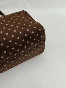 Gros plan sur le sac à main marron à pois, texture en suédine et détail des motifs blancs.