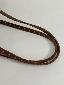 Détail de la bandoulière en suédine marron à pois, gros plan sur la texture élégante.