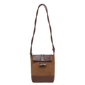 Brown suede leather crossbody bag detail view, sleek bamboo toggle closure and long strap.