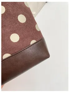 Detailed close up view of brown polka dot suede handbag with dark leather trim.