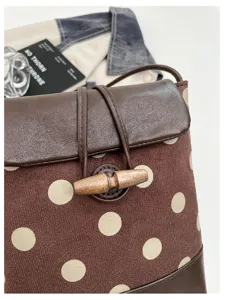 Detailed view of brown polka dot shoulder bag with leather flap and toggle button closure.