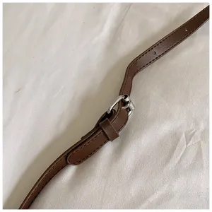Brown leather bag strap detail showing adjustable metal buckle and clean stitching work.