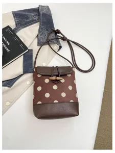 Detail view of trendy brown polka dot crossbody bucket bag featuring cute wooden toggle button.