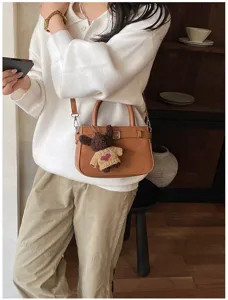 Brown suede handbag detail view, chic shoulder bag with cute bear pendant for women commuting.