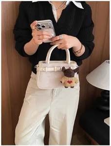 Women handbag detail showcasing premium matte texture, chic belt buckle, and cute bear charm.