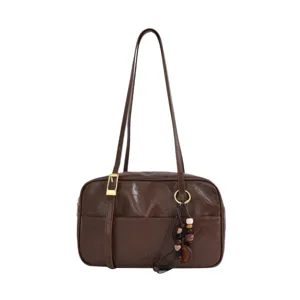 Vintage brown leather shoulder bag for women, retro underarm bag with chic charm and strap.