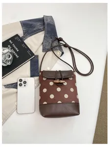 Brown polka dot bucket bag featuring PU leather trim and wooden toggle closure for women.