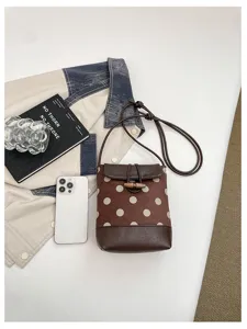 Close-up detail of brown polka dot bucket bag with stylish toggle button and fine strap.