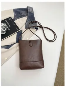 Dark brown leather bucket bag, chic minimalist crossbody purse with slender shoulder strap.